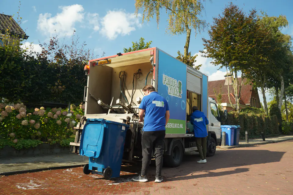 Medewerker van Frisse Kliko werkt bij de reinigingswagen langs de weg.
